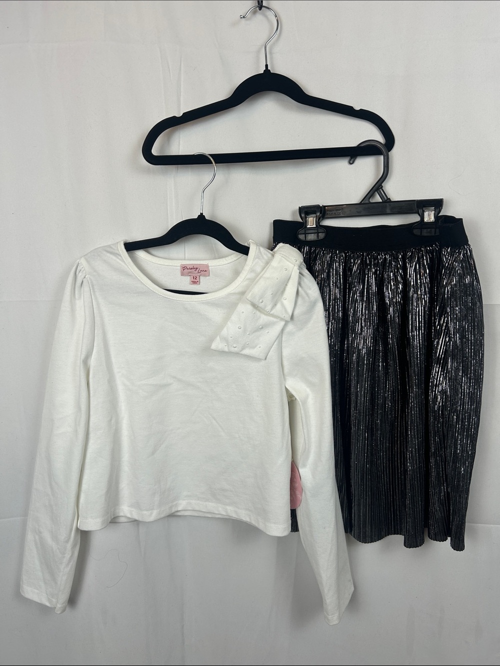 Girls' White Long-Sleeve Top with Shoulder Bow and Black Pleated Skirt.